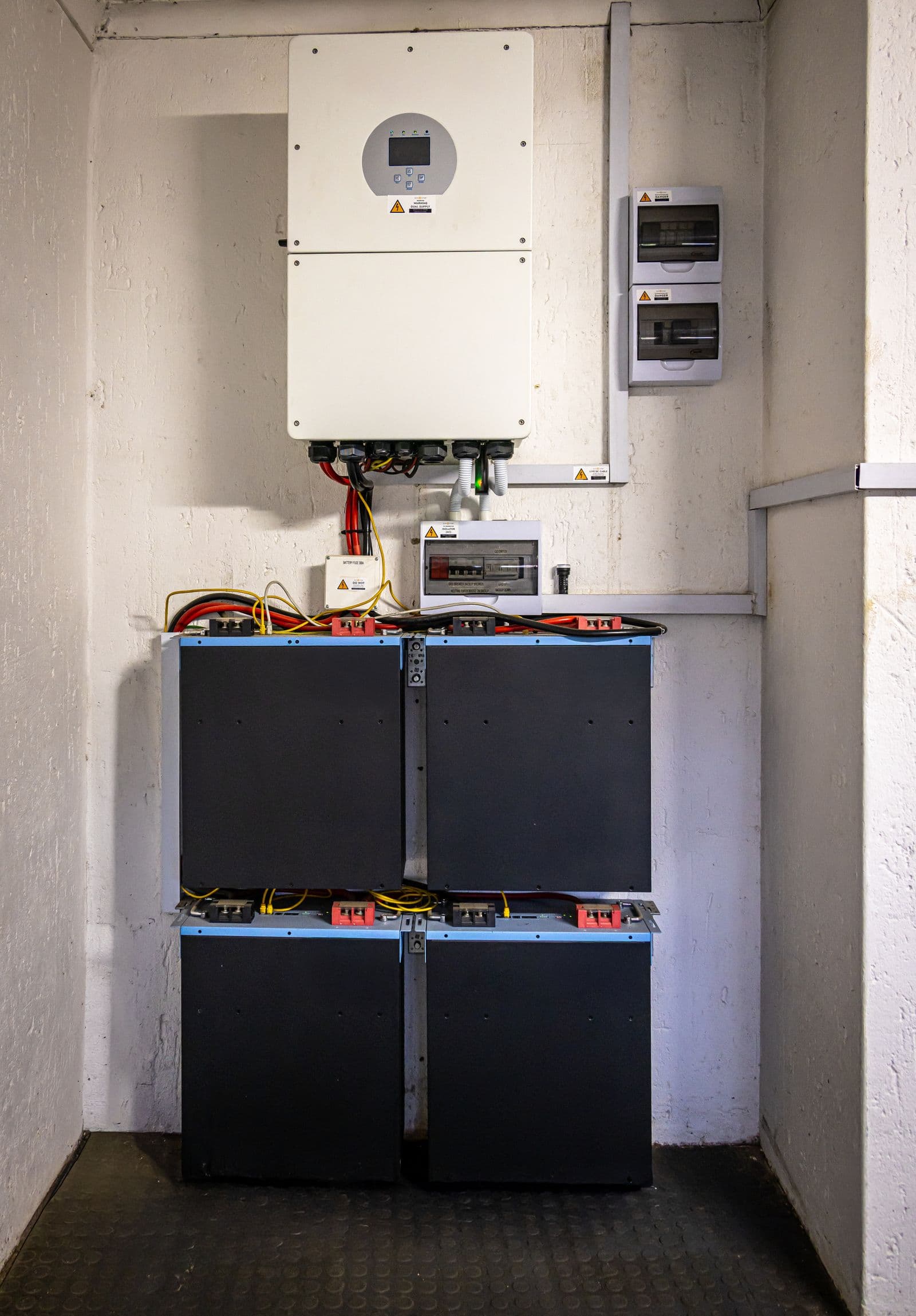 Thuisbatterijmodules met omvormer en groepenkasten aan de muur